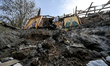 KOMYSHUVAKHA, UKRAINE - APRIL 16, 2023 - A woman salvages icons on the ruins of the Church...