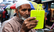 A Muslim man after purchasing a new skull cap looks into a mirror during Eid-Ul-Fitr shopp...