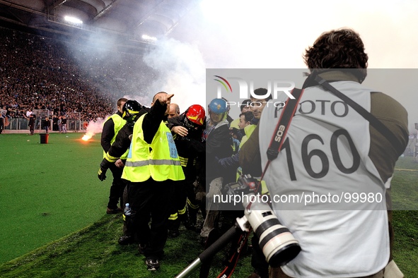 A fireman (C) is assisted by his colleagues after being hit with smoke bombs and firecrackers thrown onto the pitch by Napoli's fans, prior...