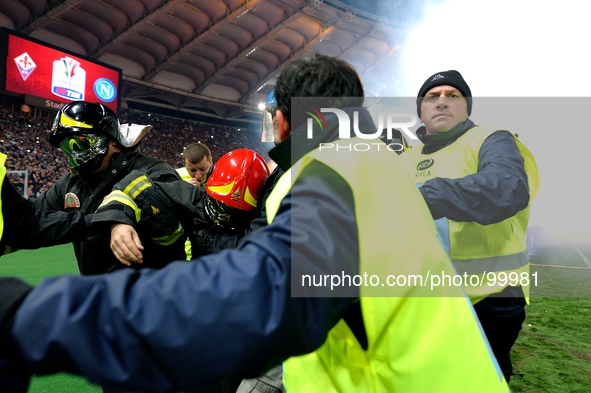 A fireman (C) is assisted by his colleagues after being hit with smoke bombs and firecrackers thrown onto the pitch by Napoli's fans, prior...